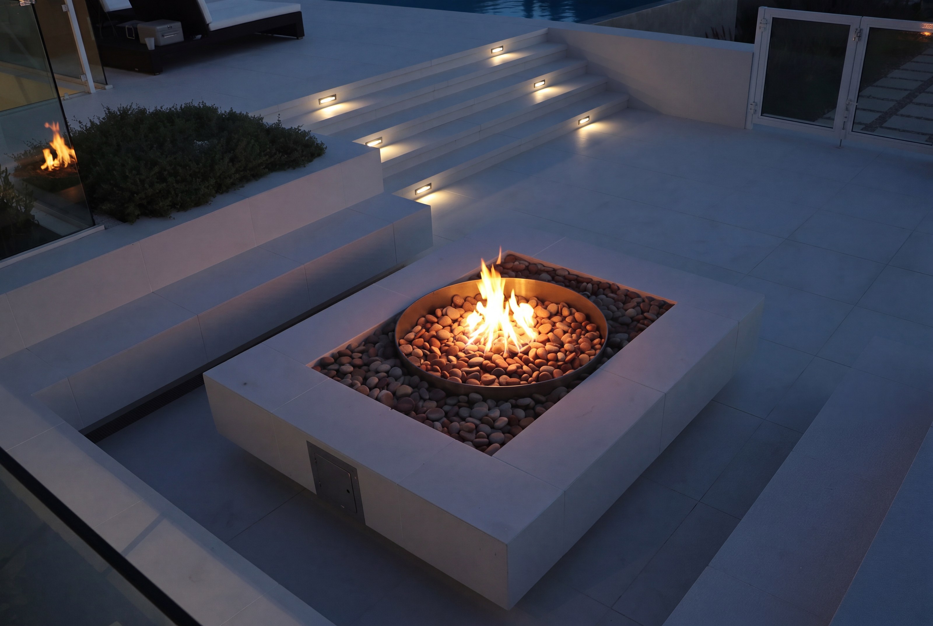 The same nano-crystallized glass patio at dusk, firepit lit and glowing